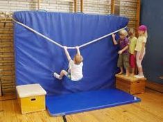 two children playing on a trampoline in an indoor area with blue tarp