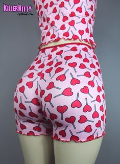 Limited, Custom-made heart lollipop lounge shorts and tank top set. Made in ultra soft knit material with printed lollipop hearts. Top and bottoms are trimmed in red picot elastic with red merrow edging and small rose detail. Also available separately. SHIPPING: Made When Ordered Please allow 5 - 7 DAYS to ship. TANK TOP LENGTH: 12" (armpit to hem) CARE: Delicate cycle, dry low. SHORTS INSEAM: 3" (fits at waist) MODEL: Mannequin has 37" hip VIEW SIZE GUIDE CARE: Delicate cycle, dry low. Cute Short Tops For Sleepover, Playful Fitted Shorts For Loungewear, Playful Red Tops For Loungewear, Pink Heart Print Bottoms For Loungewear, Cute Red Summer Sleepwear, Pink Heart Print Bottoms For Summer, Casual Pink Bottoms With Strawberry Print, Playful Stretch Loungewear Shorts, Pink Strawberry Print Bottoms For Summer