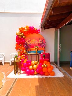 an outdoor party setup with balloons, tables and chairs on the floor in front of a wall