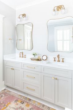 a bathroom with two sinks, mirrors and a rug on the floor in front of it