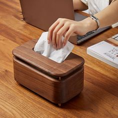 a person using a laptop on a desk with a tissue dispenser in front of them