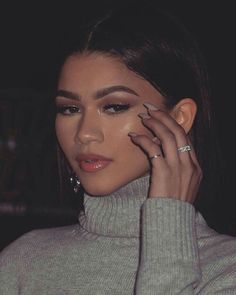 a close up of a person holding a cell phone to her ear and wearing a turtle neck sweater