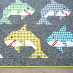 a quilted wall hanging with four different types of fish on it's sides