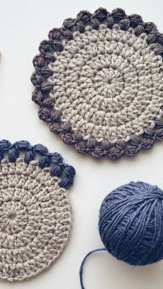 three crocheted coasters and two balls of yarn sitting on a table top