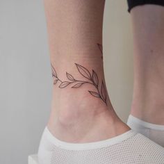 a woman's foot with a small leaf tattoo on the left side of her ankle