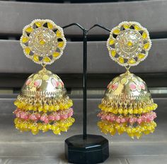 Big statement Jhumka earrings featuring a stunning yellow and pink colour combo! The gold Kundan accents make these earrings look absolutely Royal and beautiful. They are sure to impress anyone paired with an ethnic outfit! Luxury Multicolor Bollywood Jhumkas, Luxury Bollywood Multicolor Jhumkas, Fusion Style Jhumkas With Gota Work For Festivals, Fusion Style Festive Jhumkas With Gota Work, Fusion Chandbali Jhumkas With Gota Work, Festive Fusion Jhumkas With Gota Work, Festive Fusion Gota Work Jhumkas, Dual-tone Kundan Jhumkas For Wedding, Dual-tone Chandbali Jhumkas For Wedding