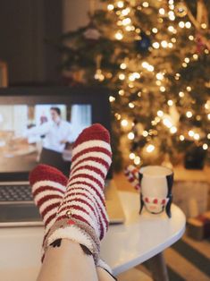 a person with their feet up on a table in front of a laptop and christmas tree