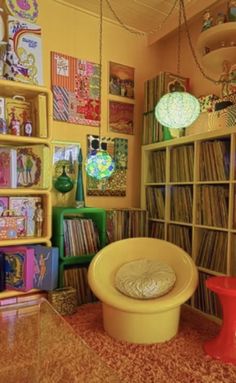 a room filled with lots of records on shelves next to a yellow chair and table