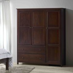 a bed sitting next to a wooden cabinet in a bedroom on top of a carpeted floor