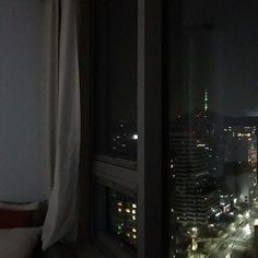 the city lights are lit up at night from this window sill in an apartment