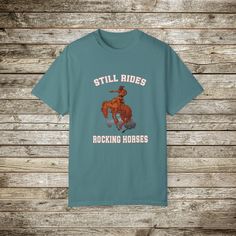 Check out my funny new wild west rodeo cowboy graphic T-Shirt, Done in the Retro Style of the 80s and 90's, this graphic western shirt, pokes gentle fun at the manly and bravery it takes to ride a bucking bronc horse. Every now and then you have to step back and say wow! Look at that guy ride! and wonder... How many rocking horse the went through as a toddler... ☺️??? Gotta love a cowboy! This super comfy comfort color tee has a relaxed fit and the cotton is soft and durable. This will make a great gift for the guy with a sense of humor! Comfort Colors Tshirts: About the Designer of FlooredByArt Studios: ☀️As an artist I try to capture the beauty of nature and the spirit of beloved animals with these stunning archival quality prints. Each design is crafted using cutting-edge digital artist Western Style Relaxed Fit Graphic T-shirt, Western Style Relaxed Fit T-shirt With Graphic Print, Western Style Crew Neck T-shirt With Graphic Print, Western Style Relaxed Fit T-shirt With Screen Print, Graphic Tee With Screen Print For Western-themed Events, Relaxed Fit Graphic Print Tops For Western-themed Events, Western Style Screen Print T-shirt For Western-themed Events, Retro T-shirt For Western-themed Summer Events, Retro Summer T-shirt For Western-themed Events