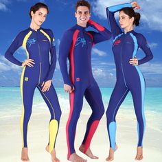 three people in wetsuits standing on the beach