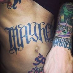 a man with tattoos on his arm and chest is holding the hand of another person