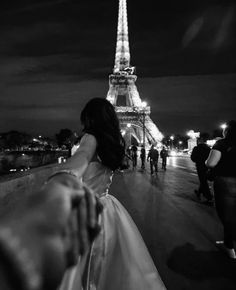 black and white photograph of a woman in front of the eiffel tower at night