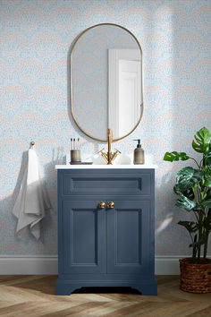 a bathroom with a blue cabinet and mirror next to a potted houseplant