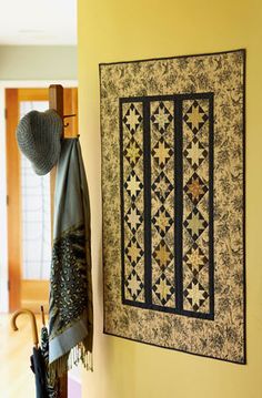 a quilt hanging on the wall next to an umbrella