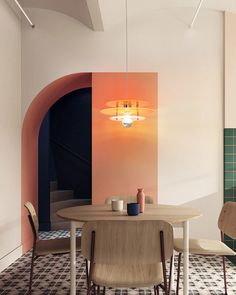 a dining room table and chairs with an archway in the wall behind it, next to a tiled floor