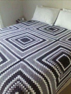 a bed with a black and white blanket on top of it