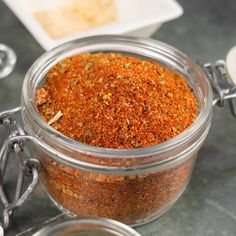 a glass jar filled with spices on top of a table