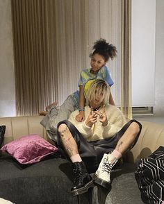 two people sitting on top of a couch next to each other