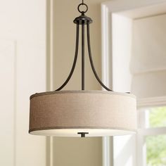 a chandelier hanging from the ceiling in a living room with beige linen shades