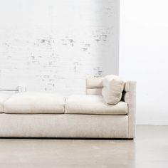 a white couch sitting next to a brick wall in an empty room with no one on it