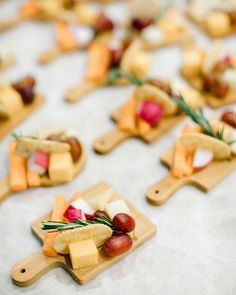 small appetizers are arranged on cutting boards with grapes and cheese in the middle