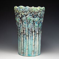 a blue vase with trees painted on the outside and inside, in front of a black background