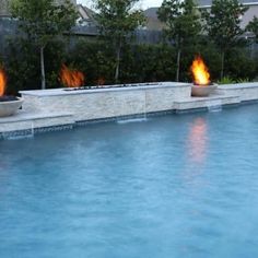 an outdoor swimming pool with fire burning in it