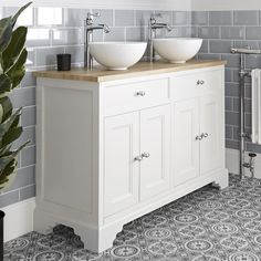 two white sinks sitting on top of a wooden counter next to a radiator