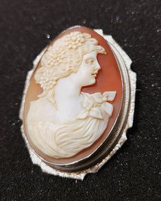 Shell, hand carved Cameo Brooch is held in a 14K bezel.  Engraving  on the frame. It features a beautiful woman with flowers.  The Brooch can also hang from a chain (not included).  The carving is delicate (just like the woman), It can be seen through the back. Woman With Flowers, Vintage Cameo, Falmouth, Cameo Brooch, Beautiful Woman, Massachusetts, Brooch Pin, Brooches, Hand Carved