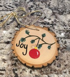 a wooden ornament with the word joy painted on it and an apple hanging from a string