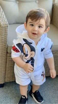 a little boy that is standing in front of a chair