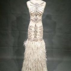 a white dress with feathers on display in a case