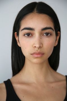 a woman with long black hair is looking at the camera