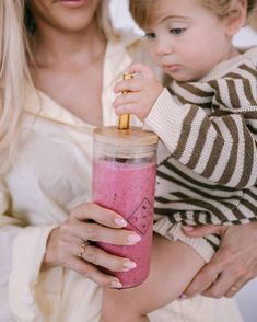 a woman holding a baby in her arms with a smoothie in front of her