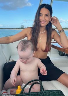 a woman sitting on top of a boat next to a baby