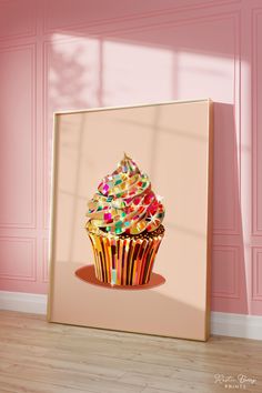 a cupcake with sprinkles on it sitting in front of a pink wall