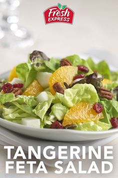 a salad with oranges, nuts and cranberries in it on a white plate