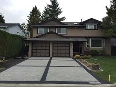 a large house with two garages in front of it and trees on the other side