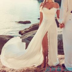 a man and woman standing next to each other in front of the ocean holding hands