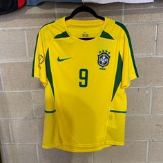 a yellow soccer jersey hanging on a brick wall next to a blue and white flag