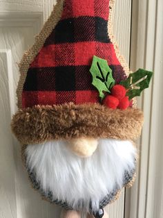 a close up of a stuffed animal wearing a christmas hat on a doorknob