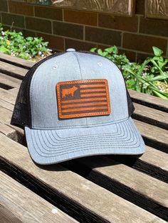 a gray and black hat with an american flag patch on it sitting on a wooden bench