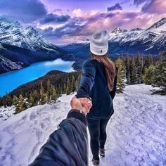 two people holding hands on top of a snow covered mountain