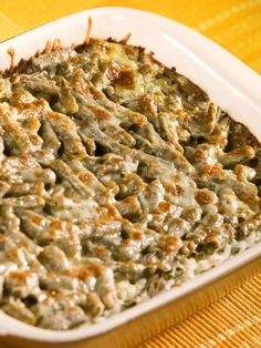 a casserole dish with meat and cheese in it on a yellow table cloth