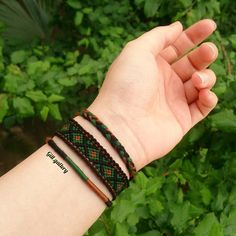 a hand holding onto a green and brown bracelet