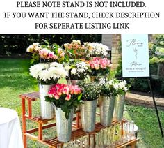 several vases filled with flowers sitting on a wooden stand in front of a sign