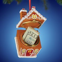 an ornament shaped like a gingerbread house hanging from a christmas tree branch