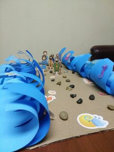 some blue streamers are sitting on a table with rocks and paper decorations around them